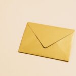 A sleek gold envelope placed on a vibrant yellow background, perfect for postal themes.